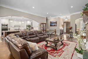 Living room featuring ornamental molding, light hardwood / wood-style floors, and a chandelier