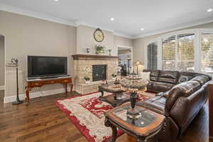 Living room featuring dark hardwood / wood-style flooring, crown molding, and a fireplace