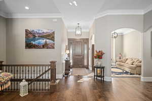 Entrance foyer with dark wood-type flooring and ornamental molding