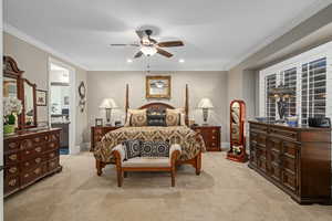 Bedroom featuring light carpet, crown molding, ceiling fan, and ensuite bathroom