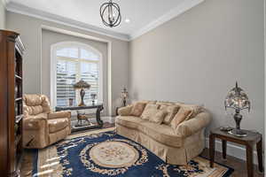 Living room with an inviting chandelier, hardwood / wood-style floors, and crown molding