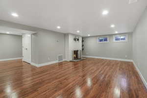 Unfurnished living room featuring a brick fireplace and hardwood / wood-style flooring