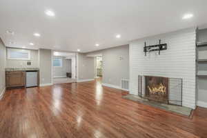 Unfurnished living room featuring hardwood / wood-style flooring and a brick fireplace