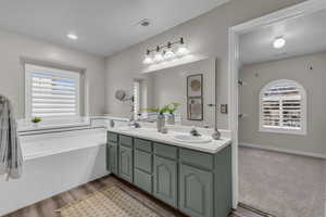 Bathroom featuring a healthy amount of sunlight, tiled bath, hardwood / wood-style floors, and vanity