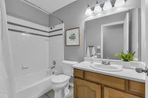 Full bathroom with tile patterned floors, toilet, vanity, and shower / bath combo