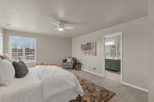 Carpeted bedroom featuring connected bathroom and ceiling fan