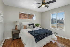 Bedroom with ceiling fan, a textured ceiling, and dark hardwood / wood-style flooring