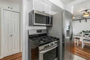 Kitchen featuring stainless steel appliances, ceiling fan, white cabinets, and dark hardwood / wood-style flooring