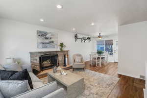 Living room featuring hardwood / wood-style flooring, a fireplace, a textured ceiling, and ceiling fan