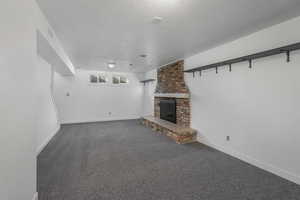 Unfurnished living room featuring dark colored carpet, a textured ceiling, and a fireplace