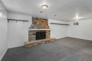 Unfurnished living room featuring a fireplace, a textured ceiling, and carpet