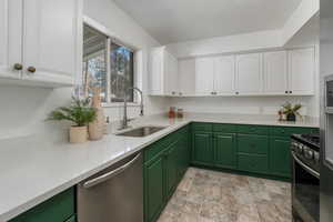 Kitchen with white cabinetry, sink, stainless steel appliances, and green cabinetry