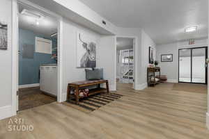 Hallway featuring a textured ceiling, light hardwood / wood-style floors, and electric panel