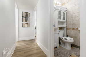 Bathroom with wood-type flooring, tile walls, vanity, and toilet