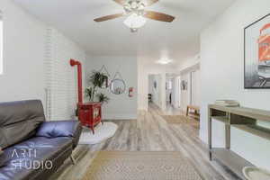 Interior space featuring light hardwood / wood-style flooring, ceiling fan, and a wood stove