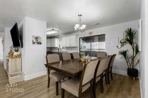 Dining area featuring a textured ceiling, an inviting chandelier, and light hardwood / wood-style flooring