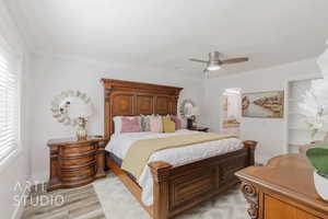 Bedroom with ceiling fan, ensuite bathroom, and light wood-type flooring