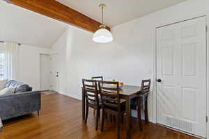 Dining space featuring vaulted ceiling with beams and dark hardwood / wood-style flooring