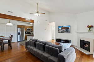 Living room featuring dark wood-type flooring, ceiling fan, and vaulted ceiling