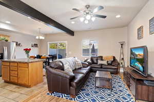 Living room with beam ceiling and ceiling fan with notable chandelier