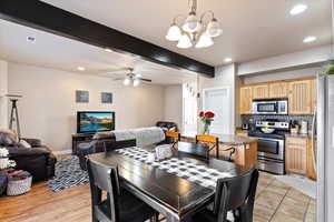 Dining room featuring beamed ceiling and ceiling fan with notable chandelier