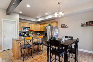 Kitchen featuring sink, stainless steel appliances, a kitchen breakfast bar, tasteful backsplash, and a notable chandelier