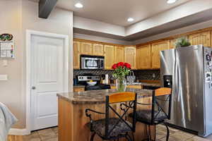 Kitchen with a center island, appliances with stainless steel finishes, a breakfast bar, and backsplash