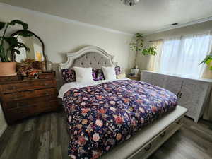 Bedroom featuring ornamental molding and dark hardwood / wood-style floors