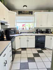 Kitchen with under cabinet range hood, white cabinets, a sink, and black appliances