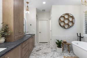 Bathroom with a sink, marble finish floor, double vanity, a freestanding bath, and recessed lighting