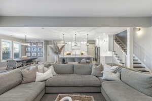 Living room featuring recessed lighting, stairway, baseboards, and a notable chandelier