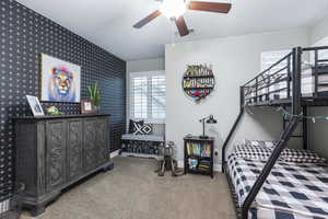 Bedroom with wallpapered walls, baseboards, carpet flooring, and an accent wall