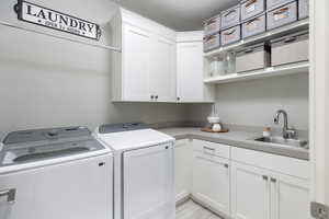 Washroom featuring cabinets, washing machine and dryer, and sink