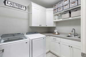 Washroom with cabinet space, a sink, and independent washer and dryer
