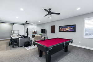 Game room featuring ceiling fan, a barn door, billiards, and carpet flooring