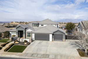 Traditional home with a tiled roof, driveway, stone siding, an attached garage, and board and batten siding