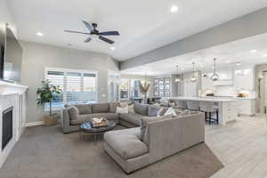 Living room with a fireplace, baseboards, ceiling fan with notable chandelier, and recessed lighting