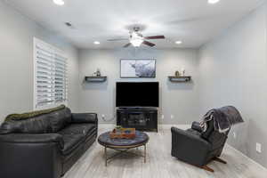 Living room with ceiling fan and light hardwood / wood-style floors