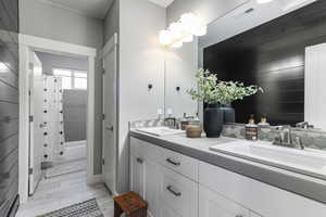 Bathroom with wood finished floors, visible vents, a sink, and double vanity