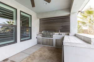 View of patio featuring ceiling fan, an outdoor kitchen, sink, and grilling area