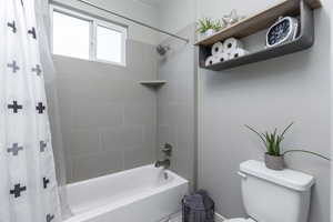 Full bathroom featuring shower / bath combination with curtain and toilet