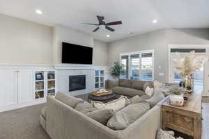 Carpeted living room with a fireplace and ceiling fan