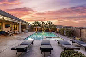 Pool at dusk with an outdoor living space, a patio area, ceiling fan, and an outdoor kitchen