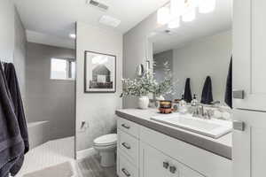 Bathroom with vanity, hardwood / wood-style floors, toilet, and a tile shower