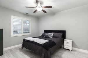 Bedroom with baseboards, a ceiling fan, visible vents, and light wood-style flooring