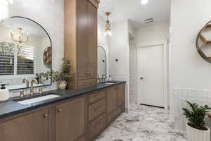 Full bath featuring double vanity, visible vents, marble finish floor, and a sink