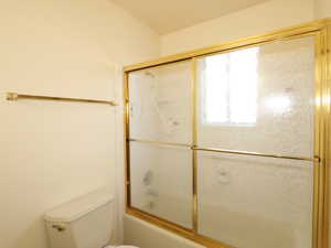 Bathroom with combined bath / shower with glass door and toilet