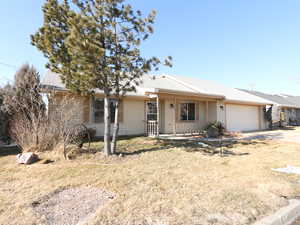 Ranch-style home featuring a garage, a front yard, and a porch