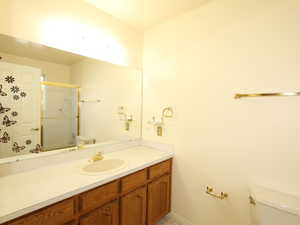 Bathroom featuring vanity, toilet, and a shower with door