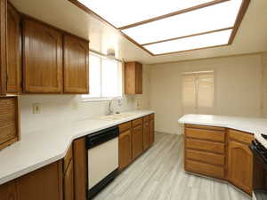 Kitchen featuring sink, dishwasher, stove, light hardwood / wood-style floors, and kitchen peninsula